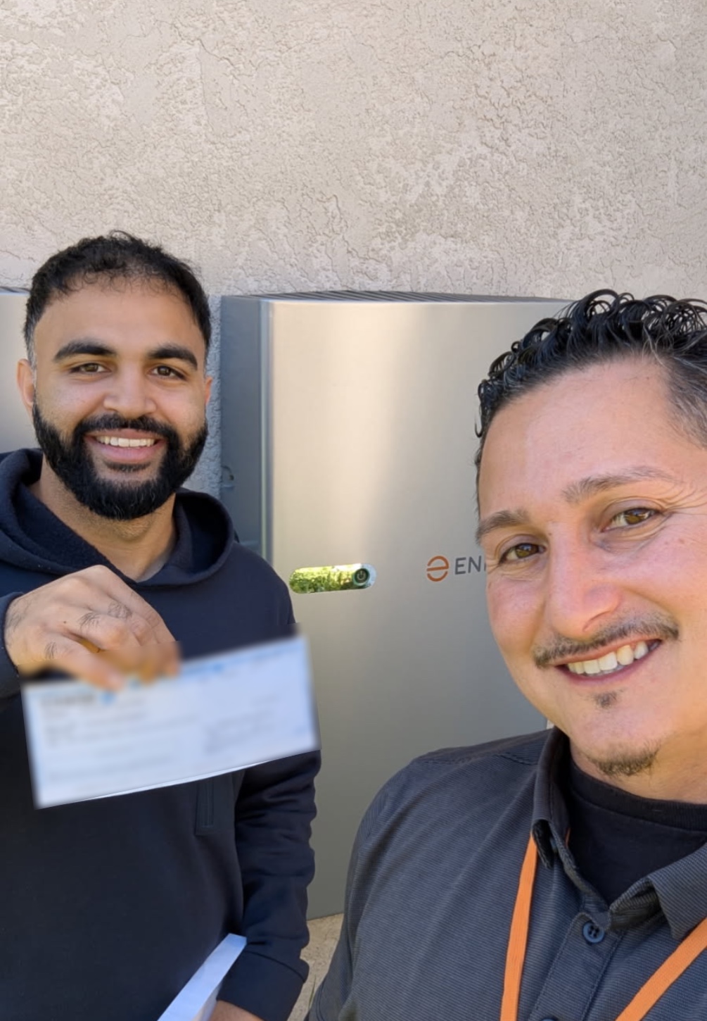 An AROS advisor and homeowner beside a home battery installation